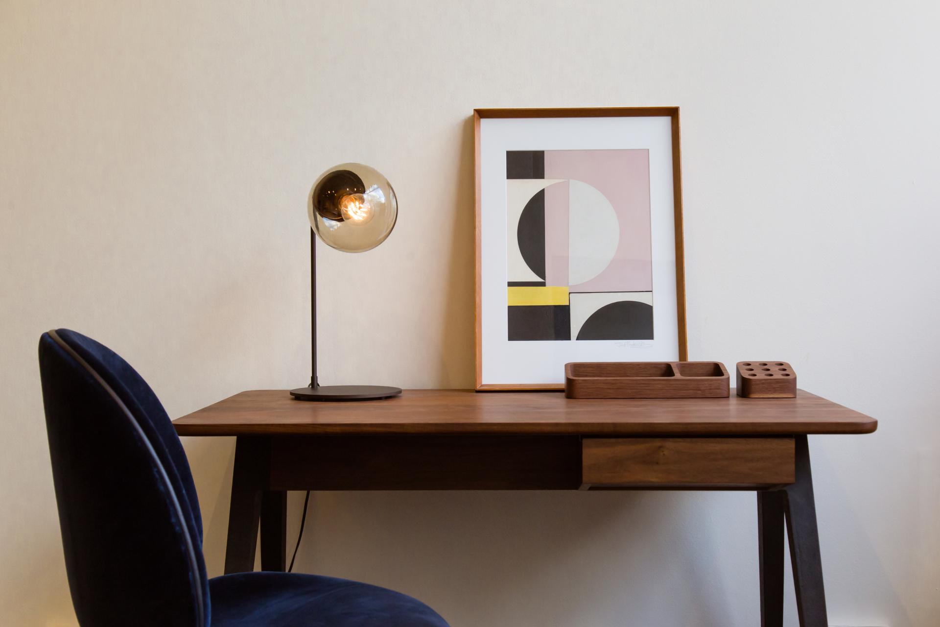 Stylish desk in SCP Pimlico Road showroom featuring modern lamp, abstract art, and elegant wooden accessories.