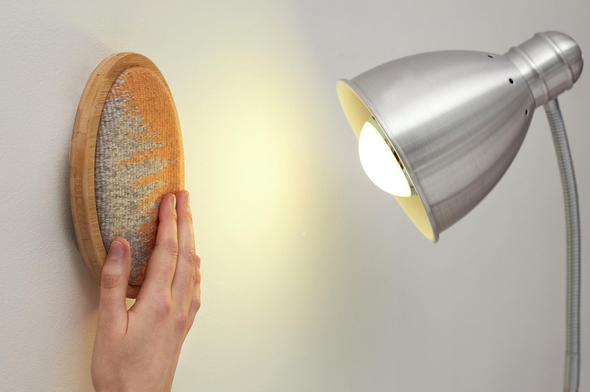 Innovative light switch design featuring a textured surface, with a hand activating the light next to a lamp.