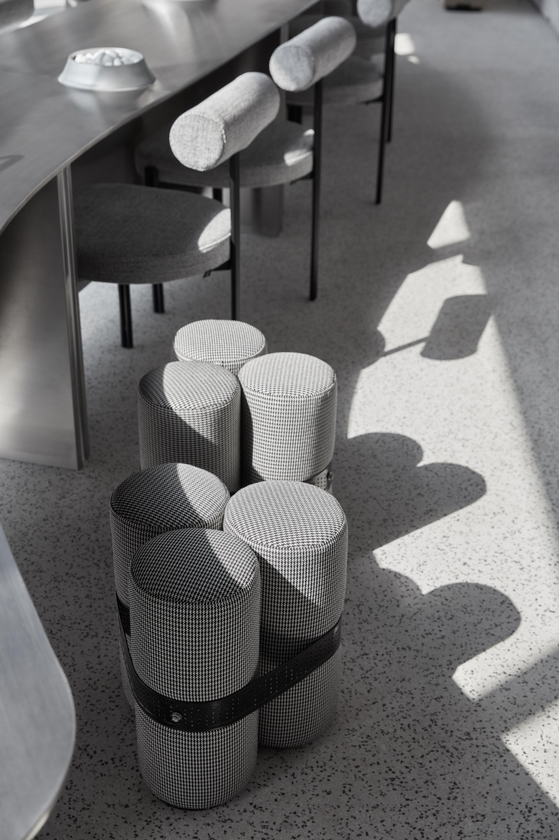 Textured, monochrome coffee stools arranged in a minimalist interior space at Drop Coffee's new Abu Dhabi location.