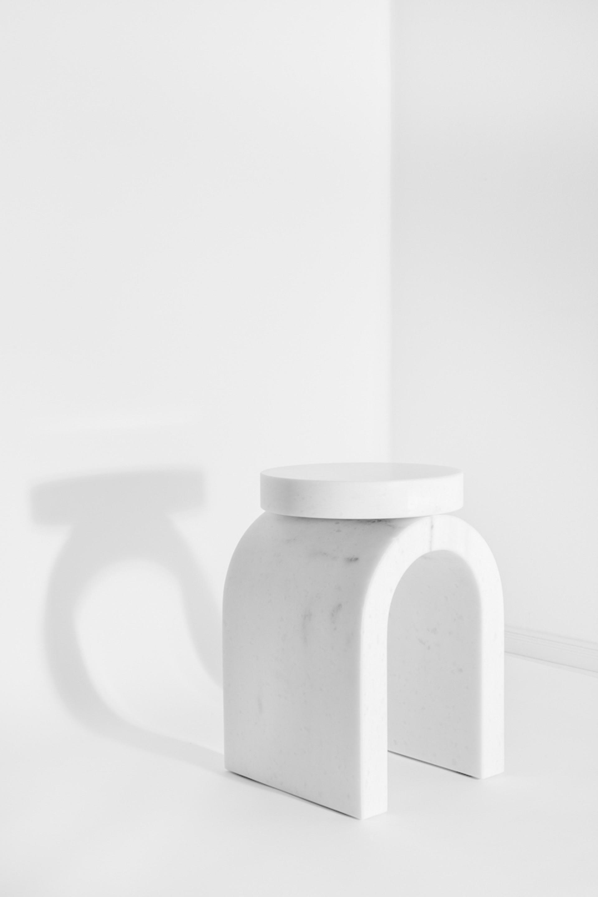 Minimalist white marble stool casting a soft shadow, showcasing contemporary German design aesthetics and craftsmanship.