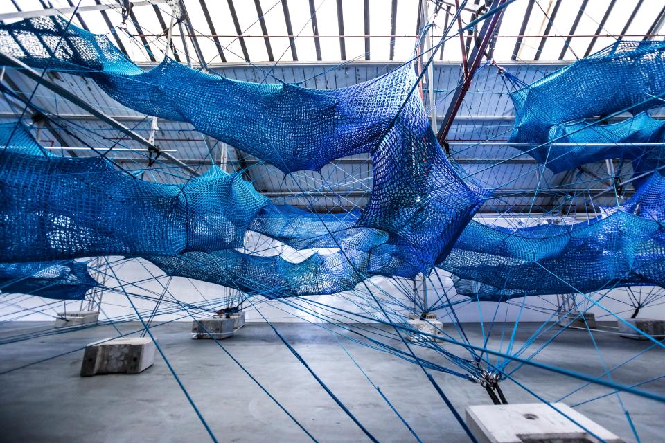 Colorful blue netting installation of Anya Hindmarch's Weave Project featured at London Fashion Week, inviting immersive interaction.