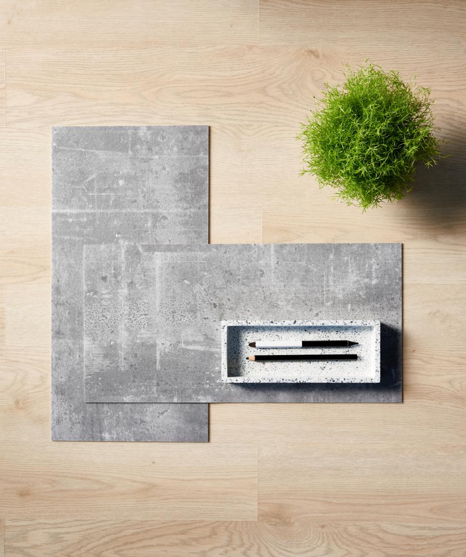 Tarkett's modular resilient flooring samples displayed with a green plant and minimalist stationery, highlighting sustainability in design.