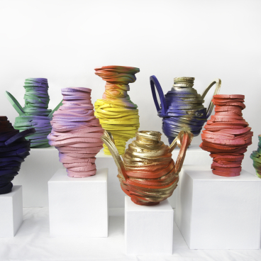 Colorful sculptural vases with twisting shapes displayed on white pedestals, featured in London Craft Week 2024.