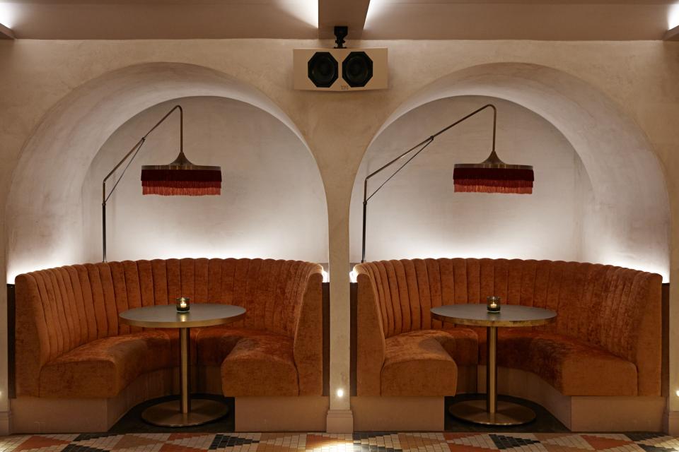 Luxurious velvet seating and unique lighting create a cozy atmosphere in The Conduit Members Club's Scandinavian-inspired interior.