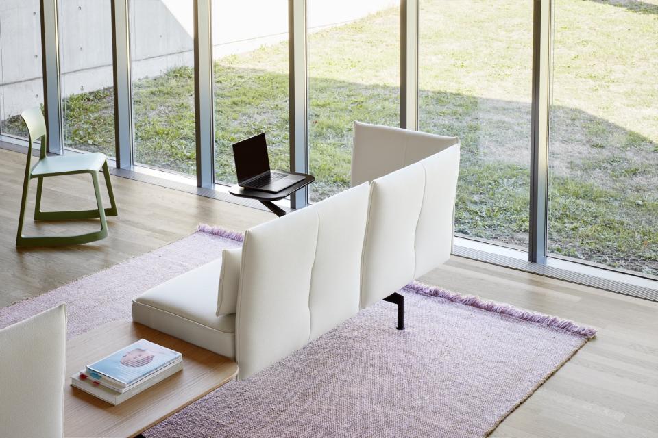 Modern white lounge seating with a minimalist design, positioned by large windows in a contemporary office space.