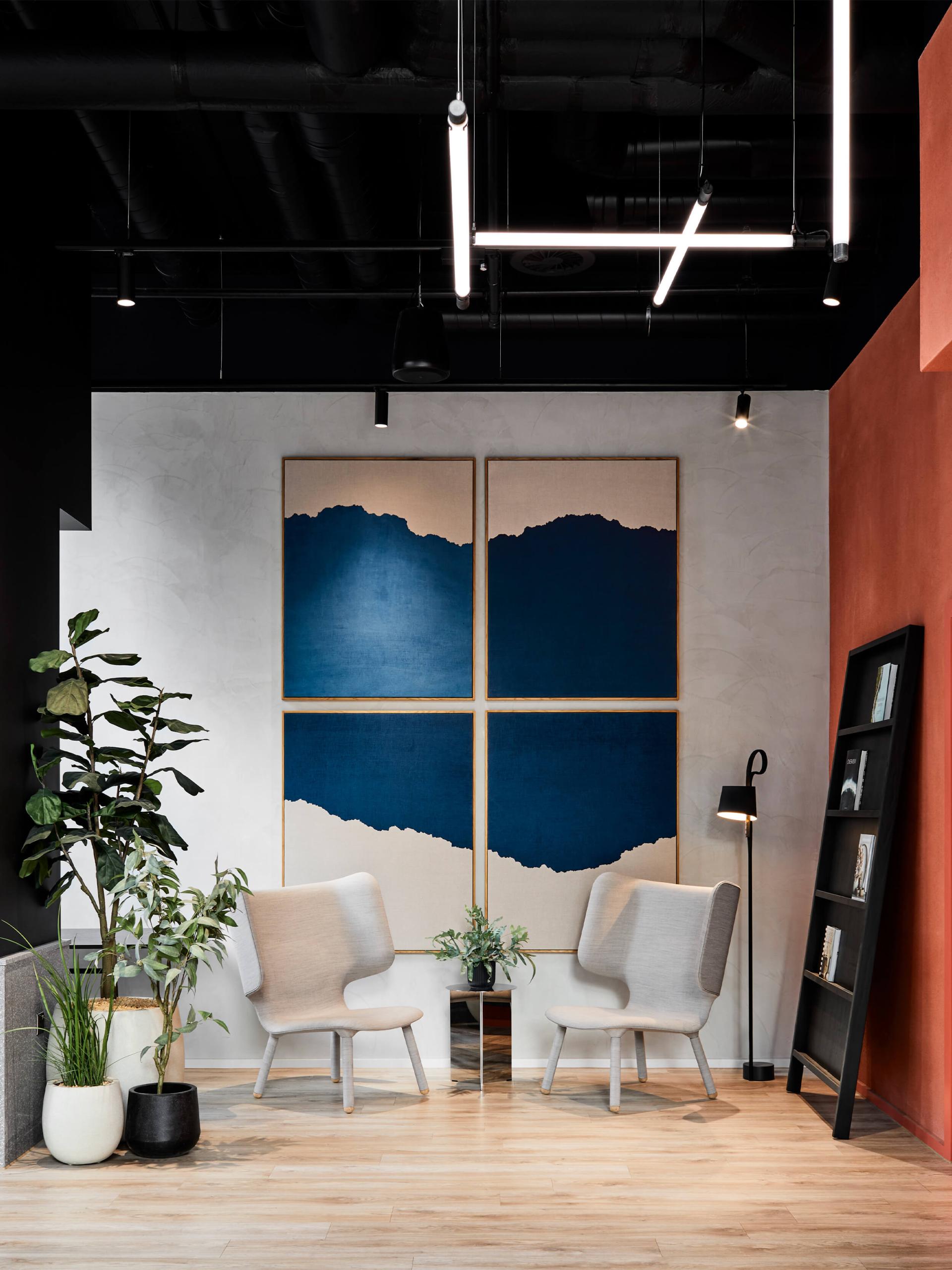 Modern interior design featuring two minimalist chairs, plants, and abstract wall art in a stylish studio environment.