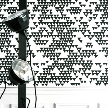 Bold black and white triangular pattern wallpaper designed by Sacha Walckhoff, paired with modern lighting fixture.