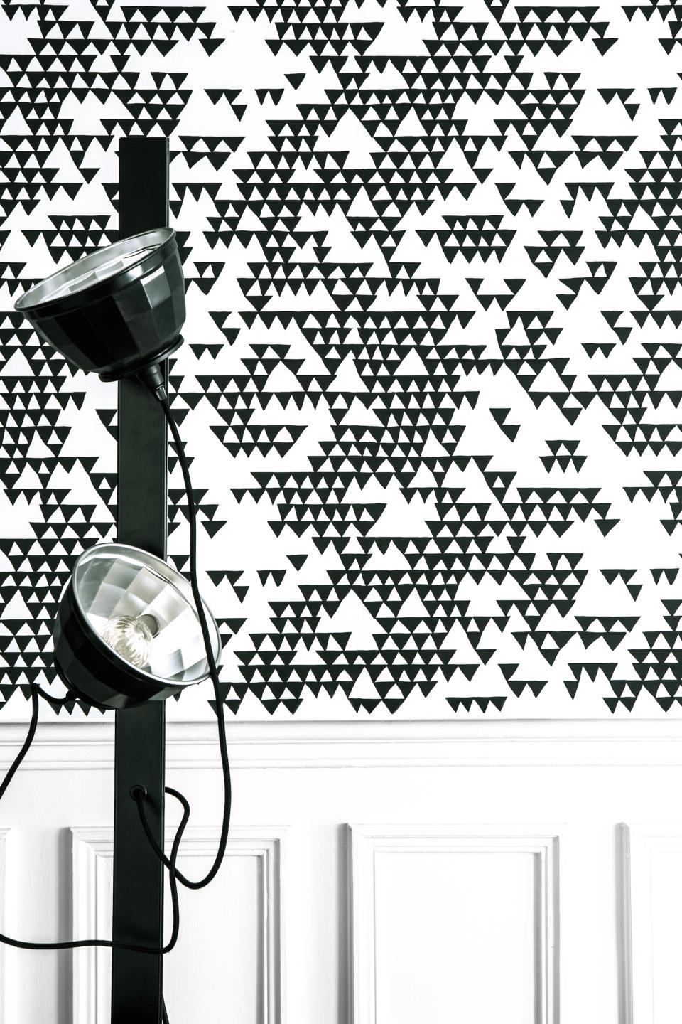 Bold black and white triangular pattern wallpaper designed by Sacha Walckhoff, paired with modern lighting fixture.