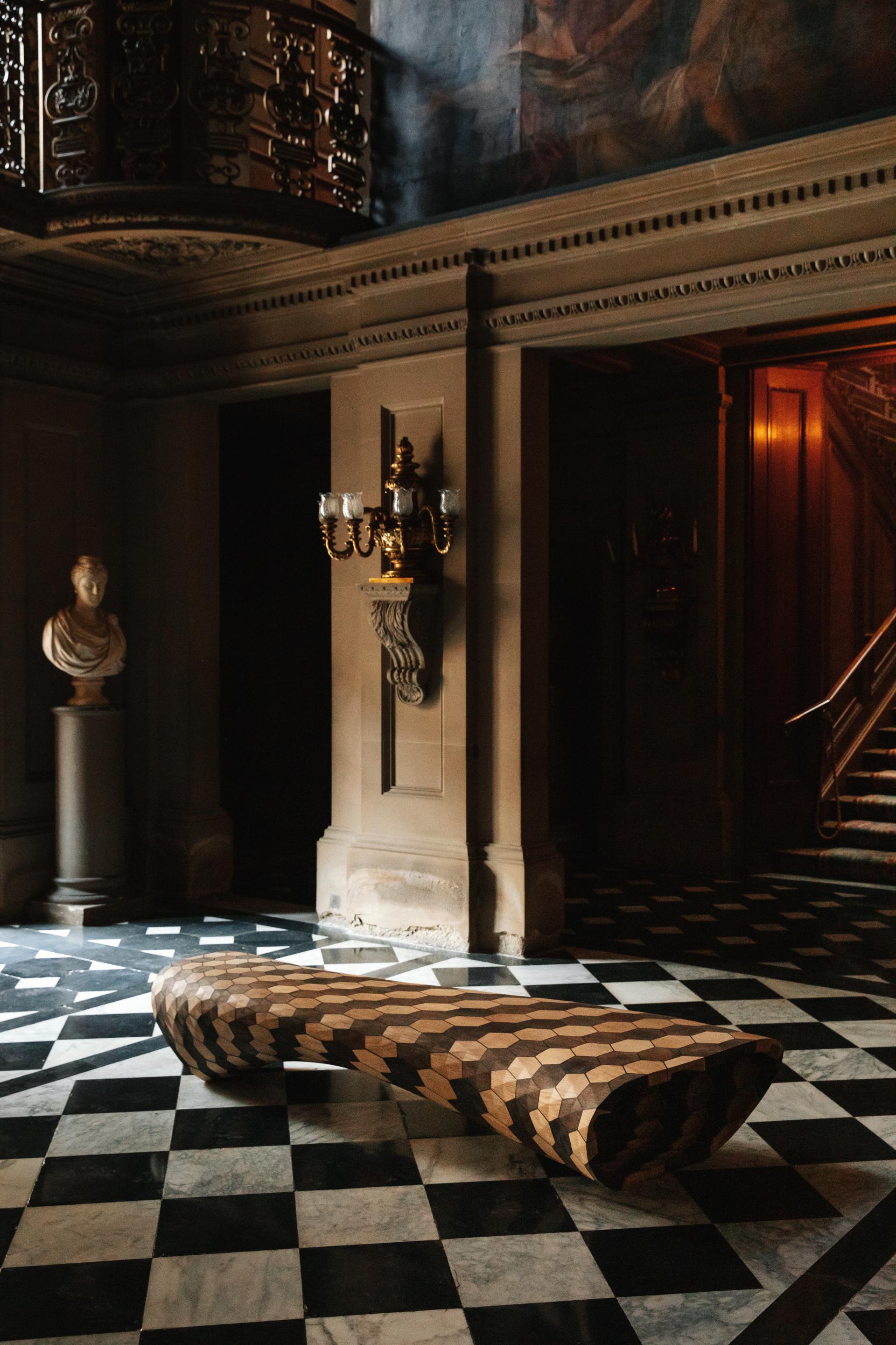 Sculptural wooden bench on a marble floor in the historic Chatsworth House, highlighting its rich heritage and artistic design.