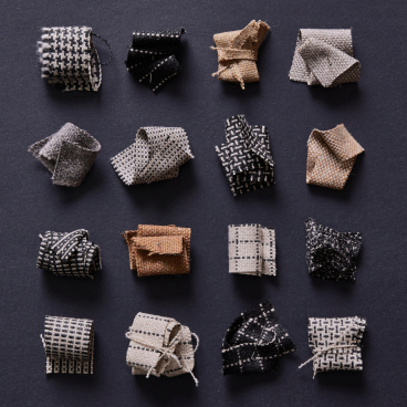Collection of sustainable mini fabric samples in monochrome patterns by Camira, displayed on a dark background.