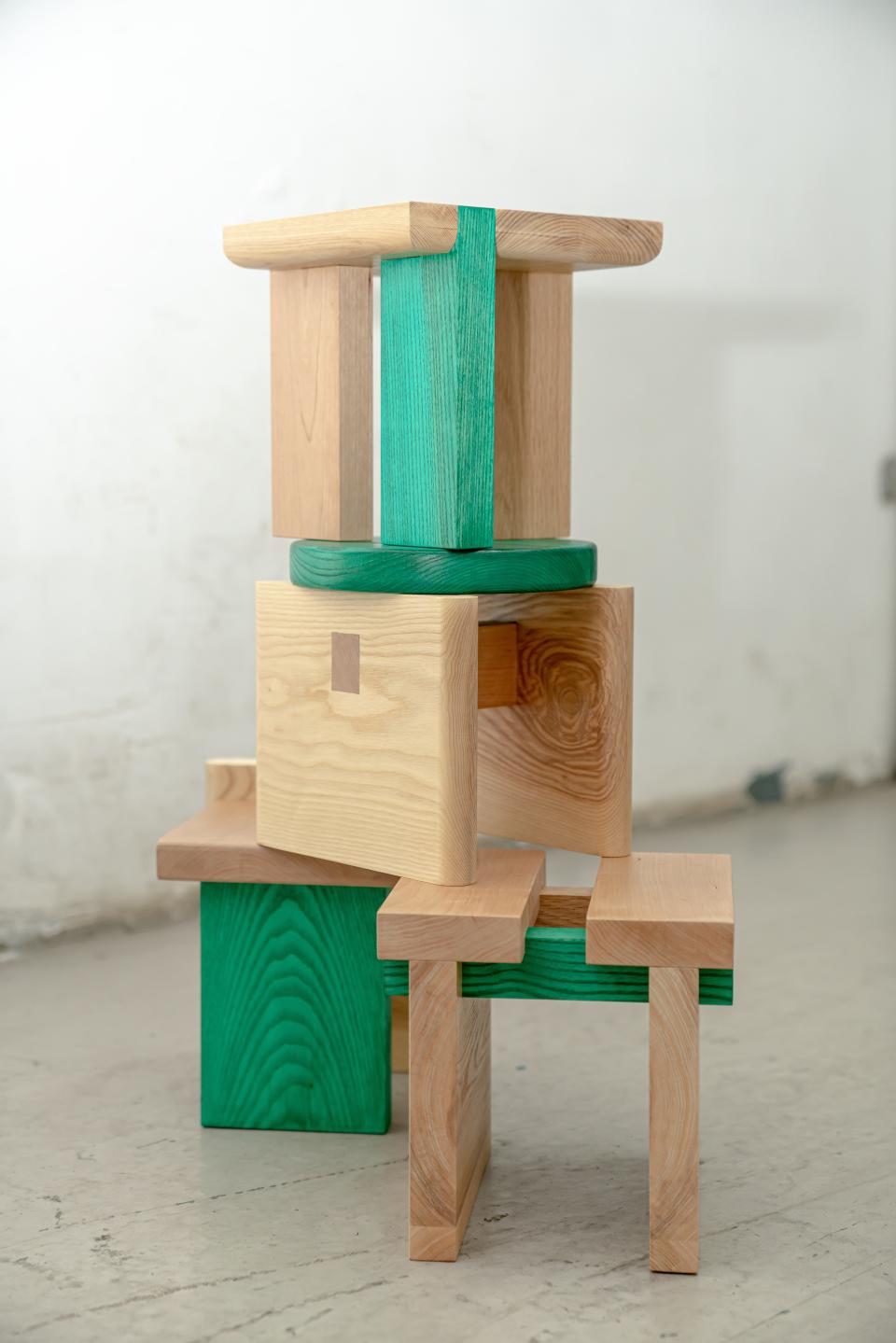 Colorful wooden mini-stools stacked creatively, showcasing versatile design and craftsmanship by Napp Studio for adaptable furniture solutions.