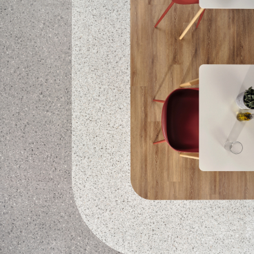 Stylish dining area featuring terrazzo and wooden floors, complemented by modern red chairs and indoor plants.
