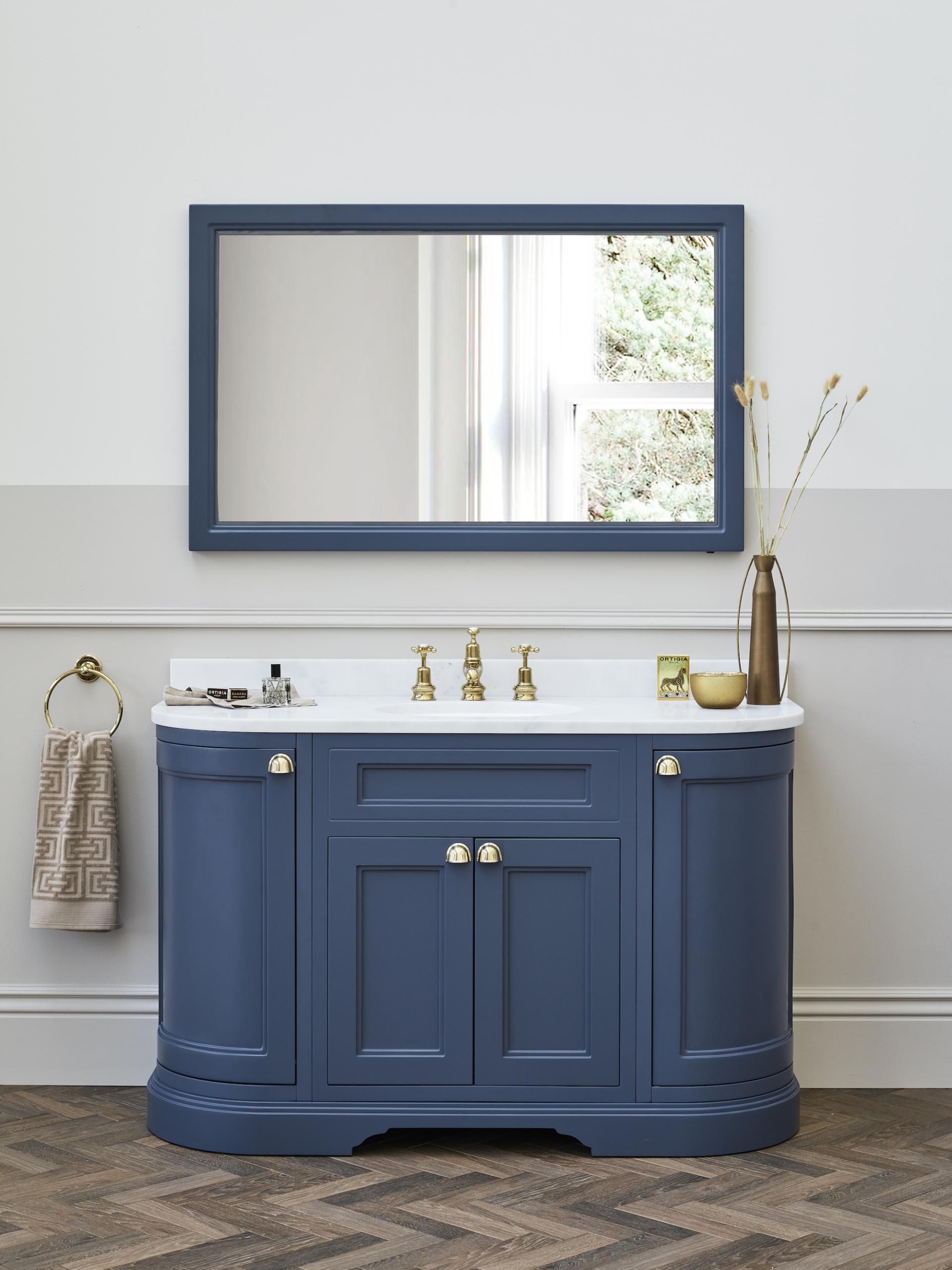 Elegant blue bathroom vanity with a marble countertop, brass fixtures, and a framed mirror above, enhancing modern design.