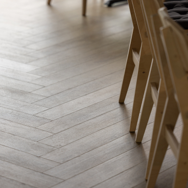 Stylish wooden flooring with light herringbone patterns, complemented by modern seating in The English Spirit Distillery.