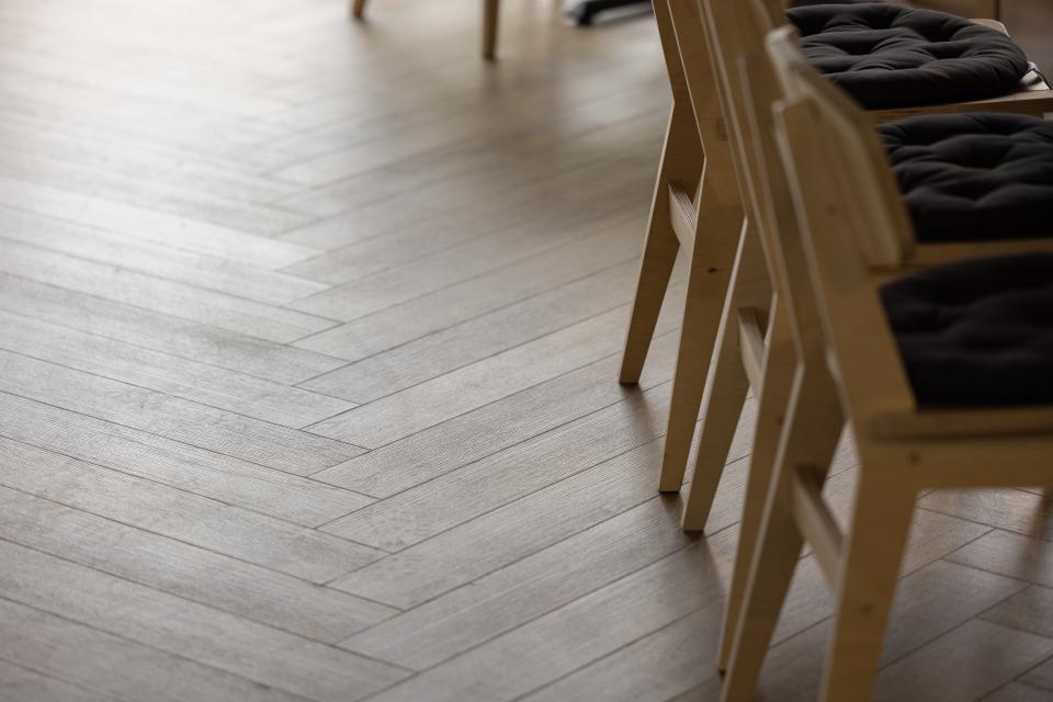 Stylish wooden flooring with light herringbone patterns, complemented by modern seating in The English Spirit Distillery.