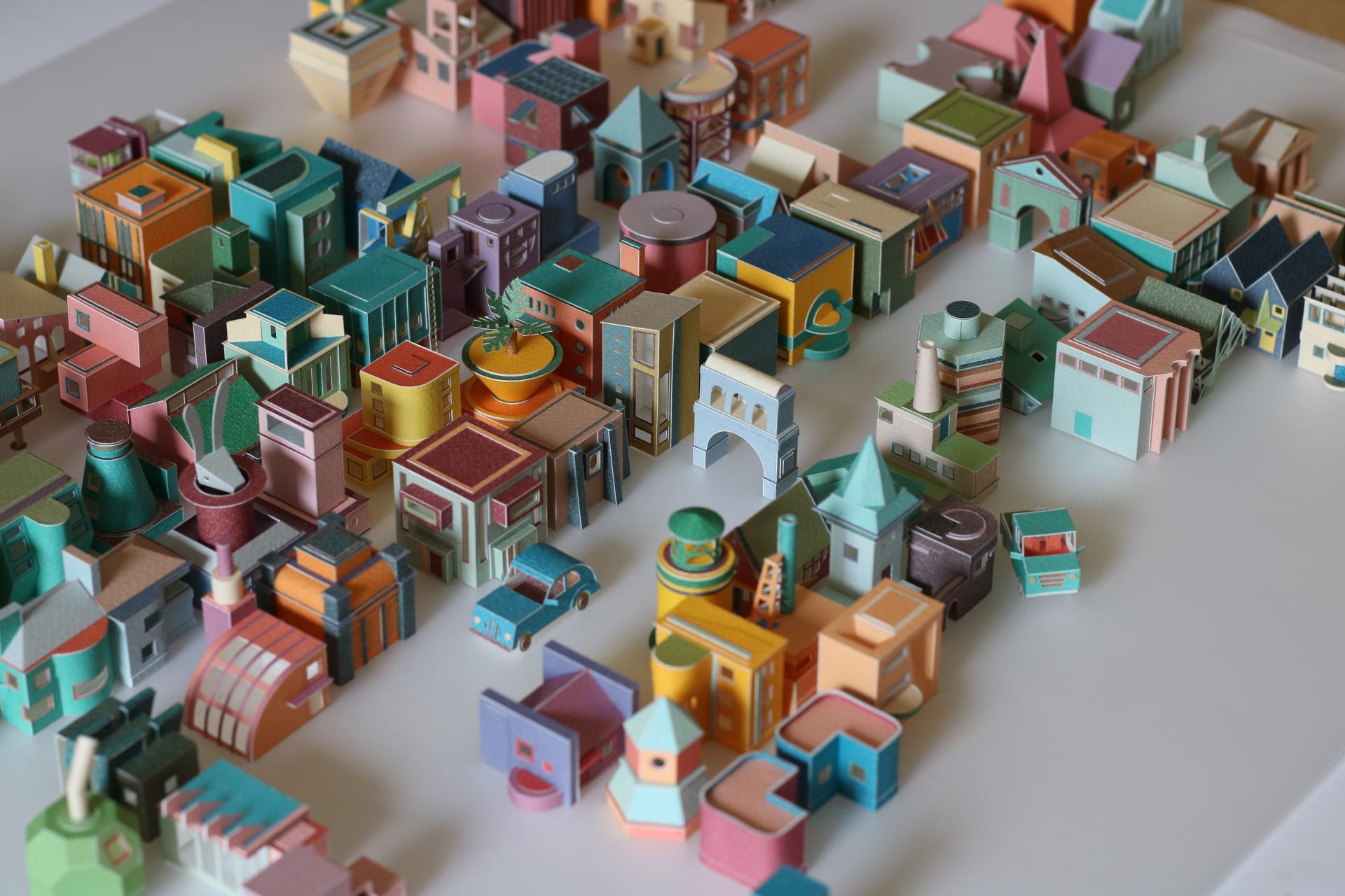 Colorful miniature paper buildings arranged intricately, highlighting the creativity and detail of model maker Charles Young's architectural vision.