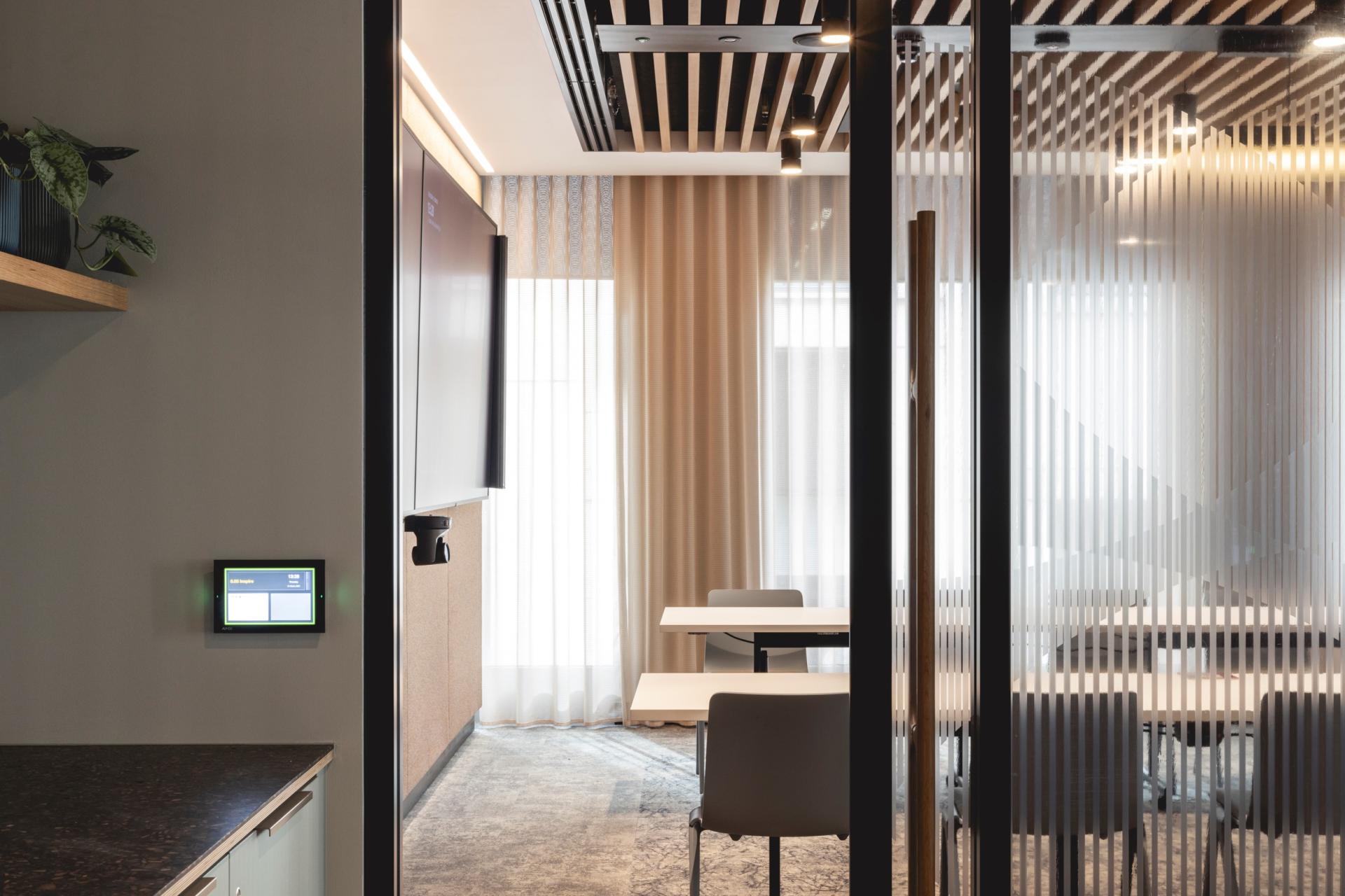 Modern office workspace featuring Art Deco-inspired design elements, glass partitions, and a light-filled meeting area.