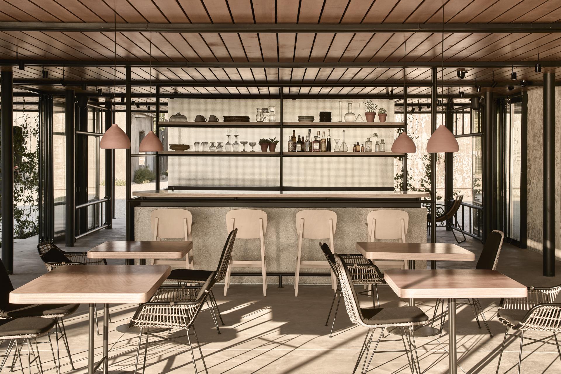 Stylish café interior in a converted wine factory, featuring wooden tables, modern chairs, and decorative shelves.