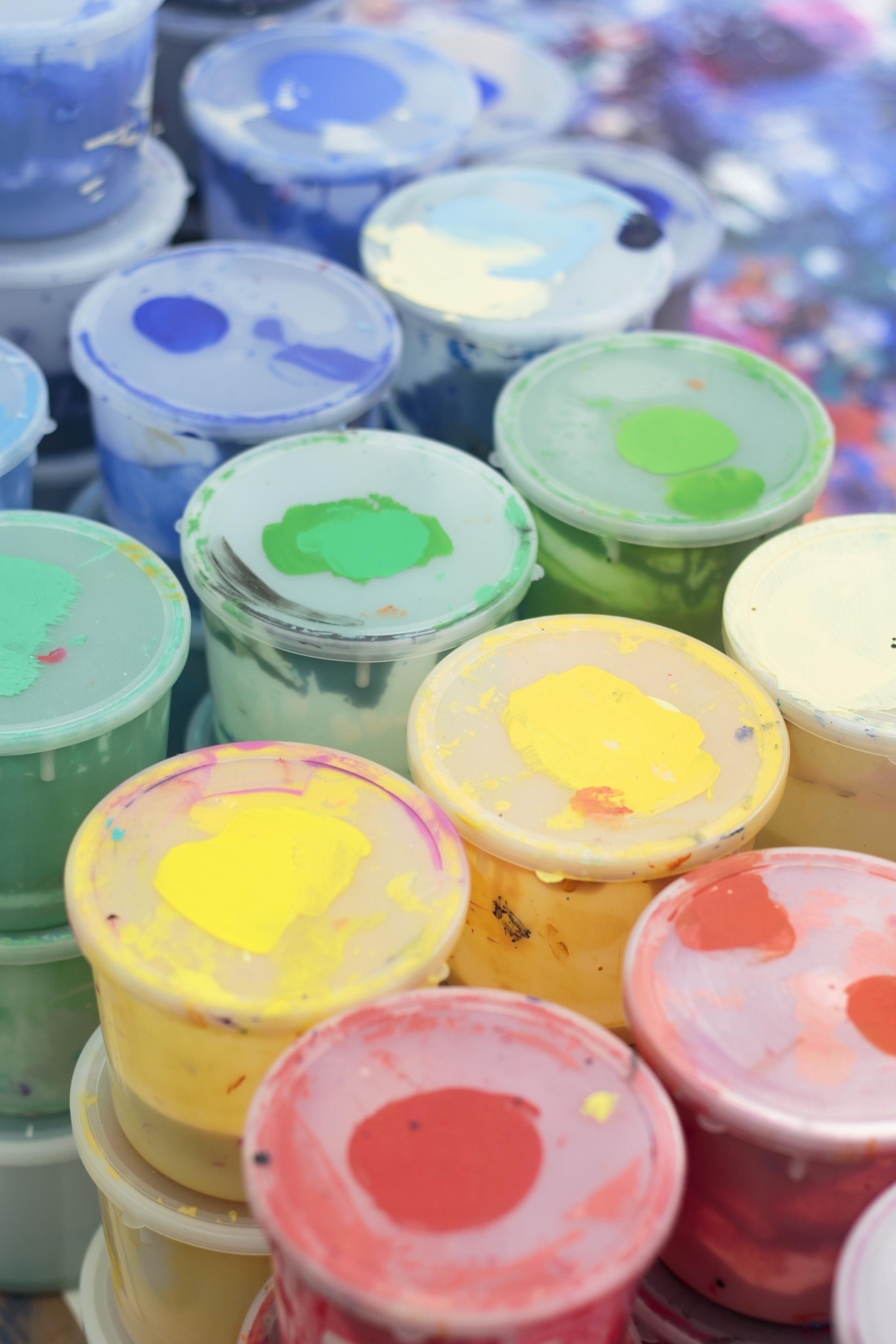 Colorful paint containers showcasing various shades, representing the vibrant inspiration behind Kvadrat's Divina Melange collection.