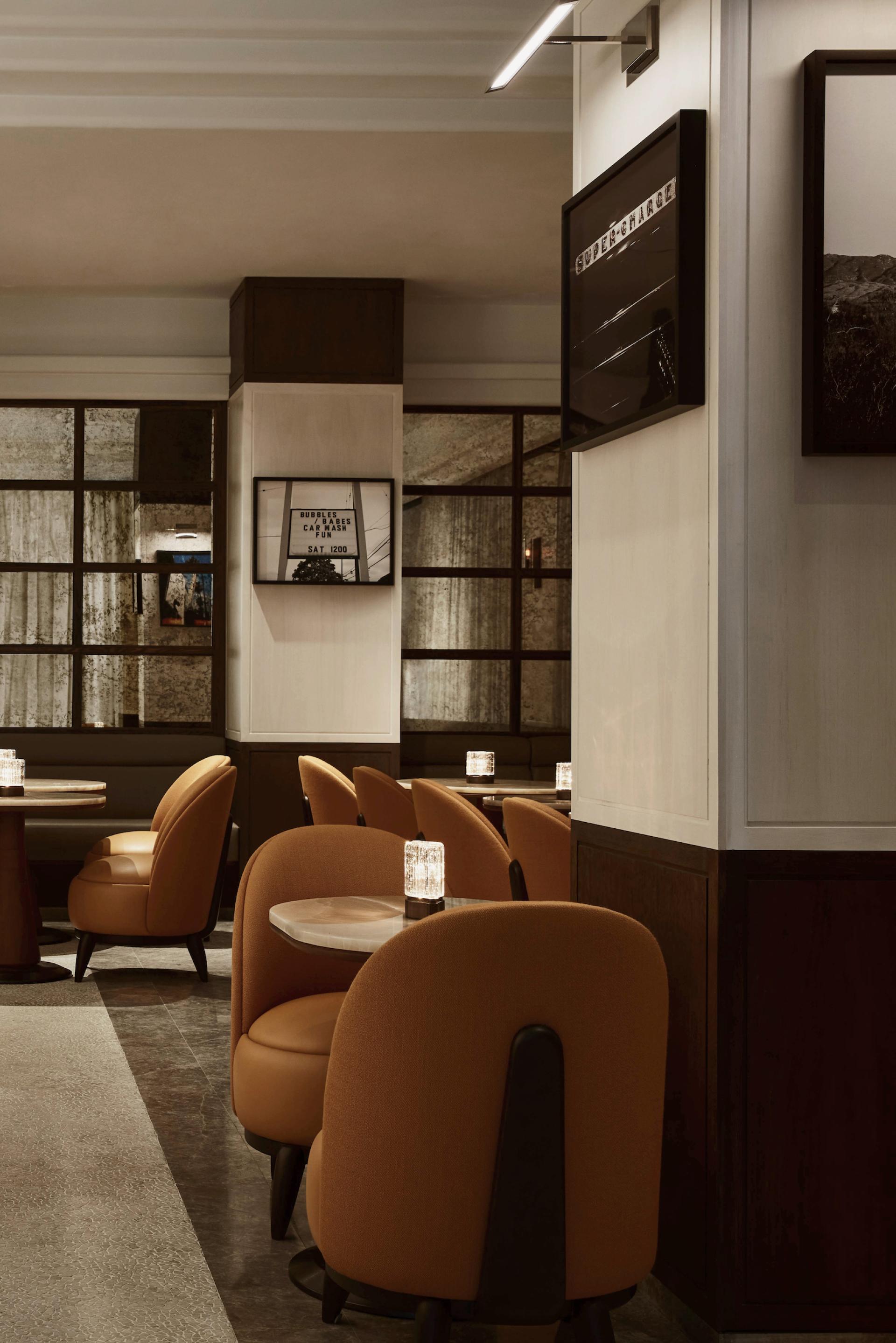 Elegant interior of The Maybourne Bar featuring art deco design, plush orange chairs, and ambient lighting.