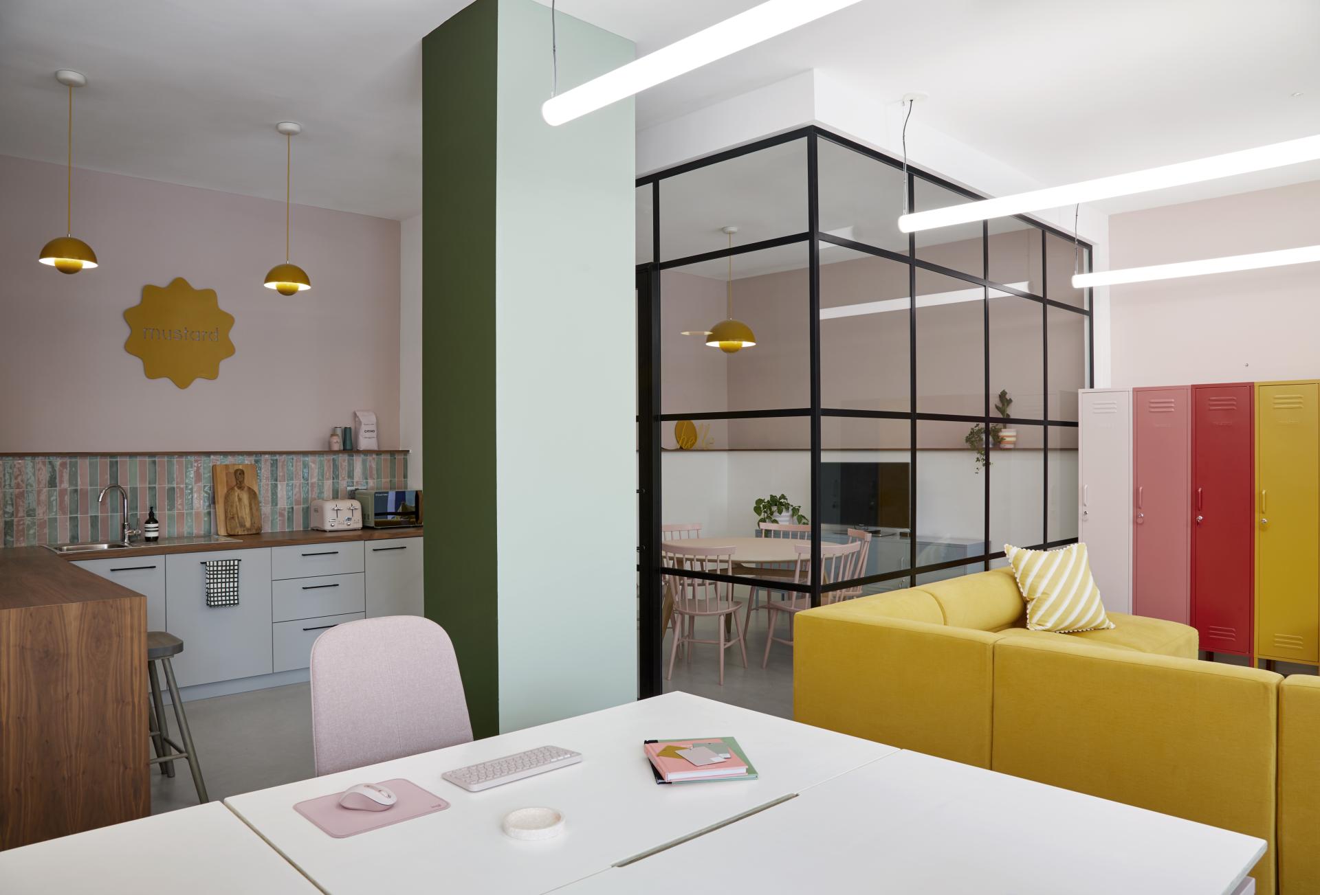 Brightly colored office space featuring a yellow sofa, modern kitchen, and collaborative workspace inspired by creativity and collaboration.