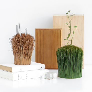 Stylish desk arrangement featuring plant-like pencil holders, books, and wooden decor, exploring the concept of vessels.