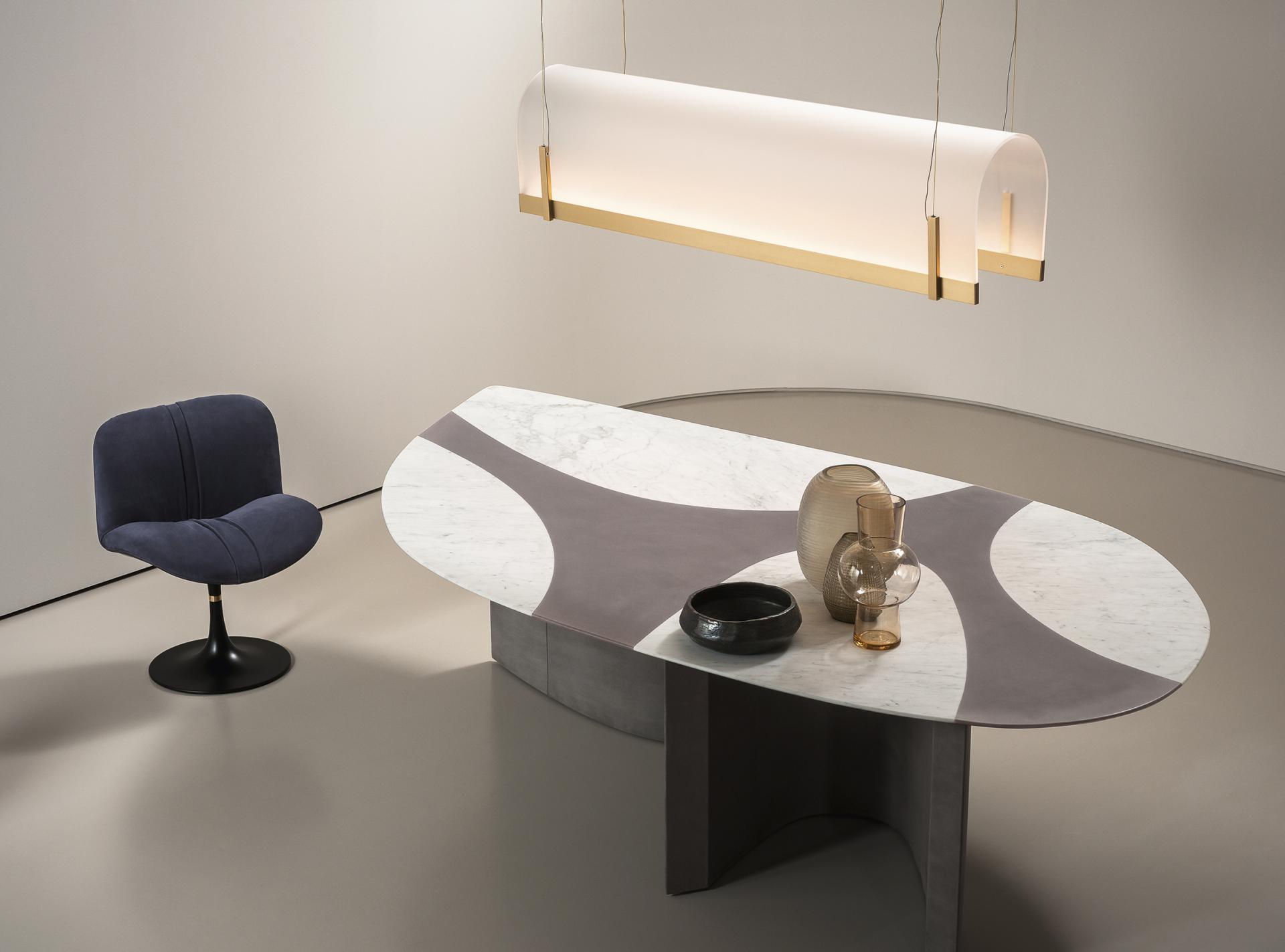 Sleek marble table with decorative vases and a modern chair, featured in Baxter's luxury design showcase at Silvera, London.