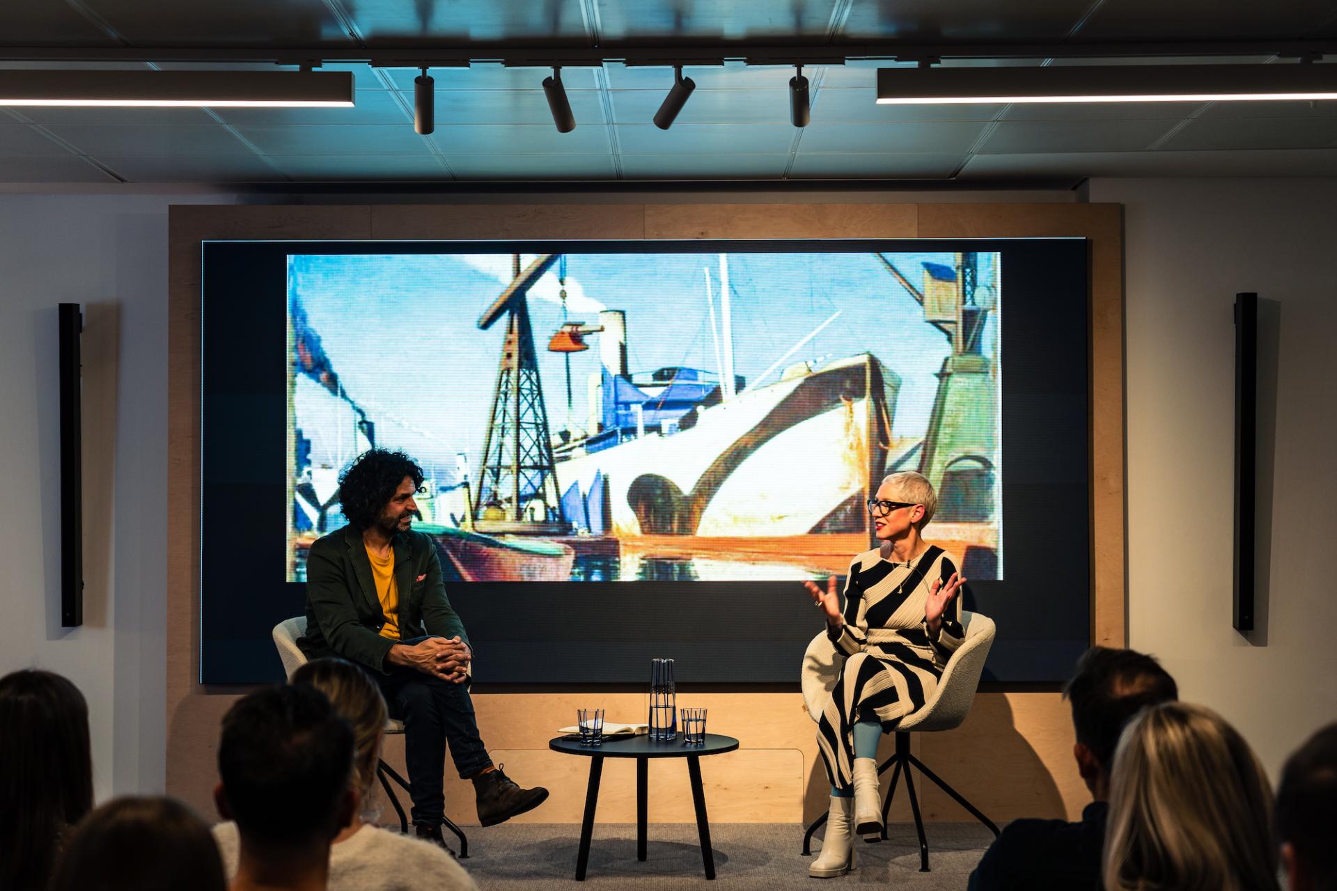 Anna Campbell-Jones discusses design and retail trends at Material Source Studio Glasgow, with artwork displayed in the background.