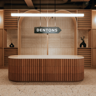Modern reception desk with 'Dentons' sign, featuring wood accents and a stylish interior design in Edinburgh workspace.