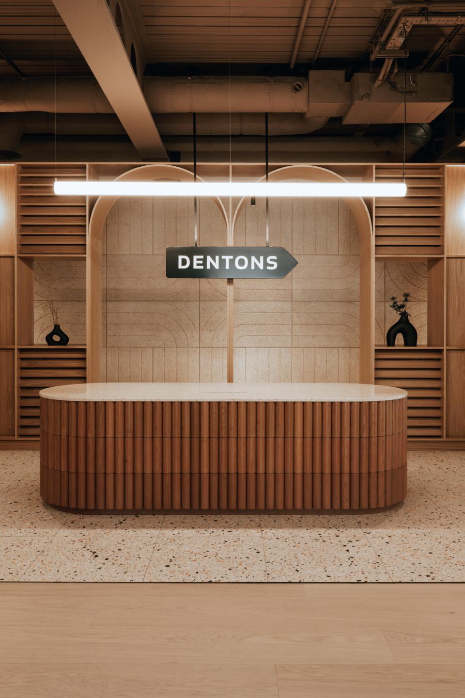 Modern reception desk with 'Dentons' sign, featuring wood accents and a stylish interior design in Edinburgh workspace.
