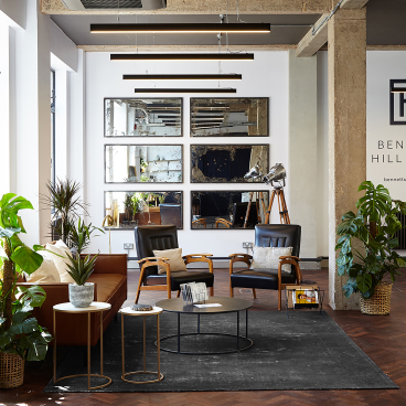 Chic loft-style office space featuring modern furniture, plants, and decorative mirrors, highlighting Run For The Hills' design transformation.