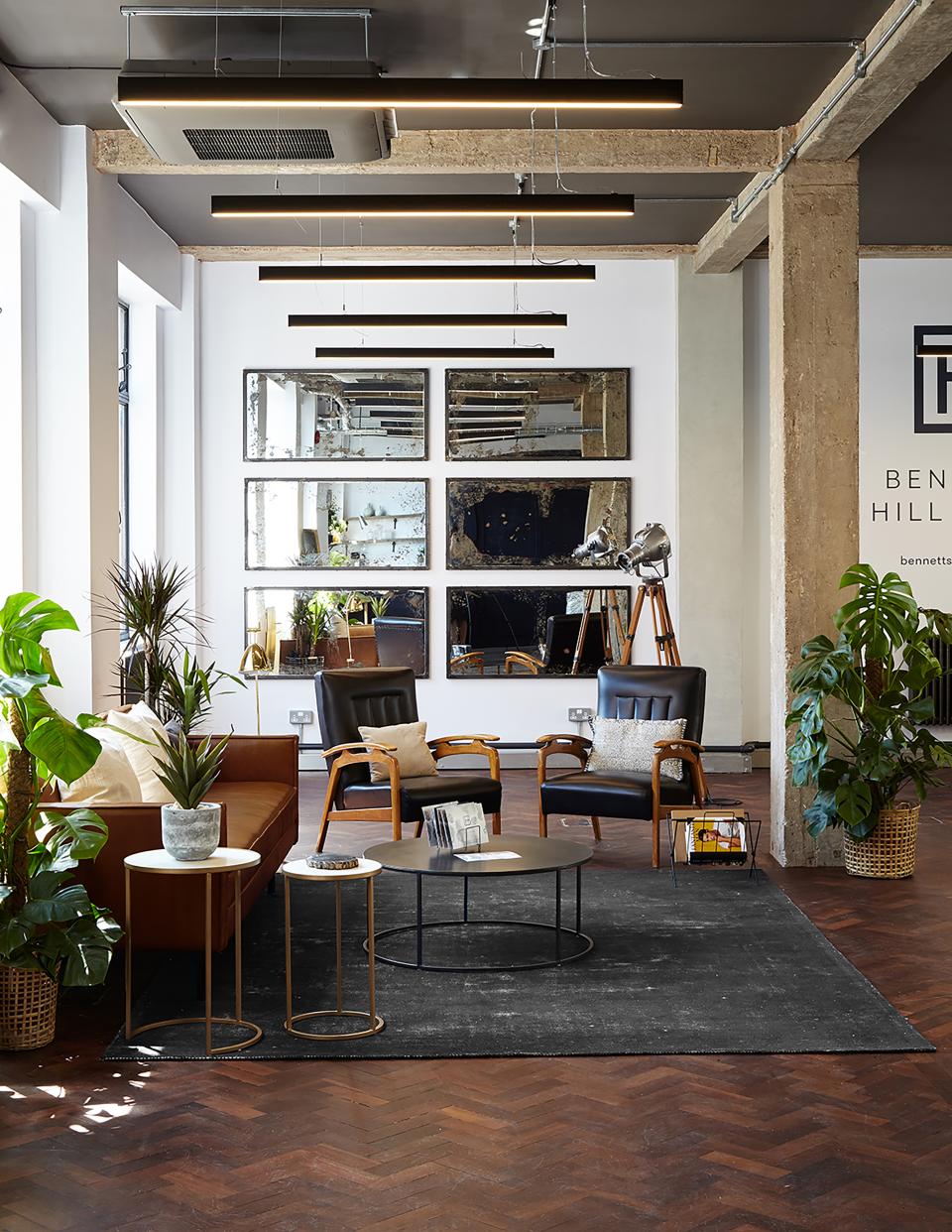 Chic loft-style office space featuring modern furniture, plants, and decorative mirrors, highlighting Run For The Hills' design transformation.