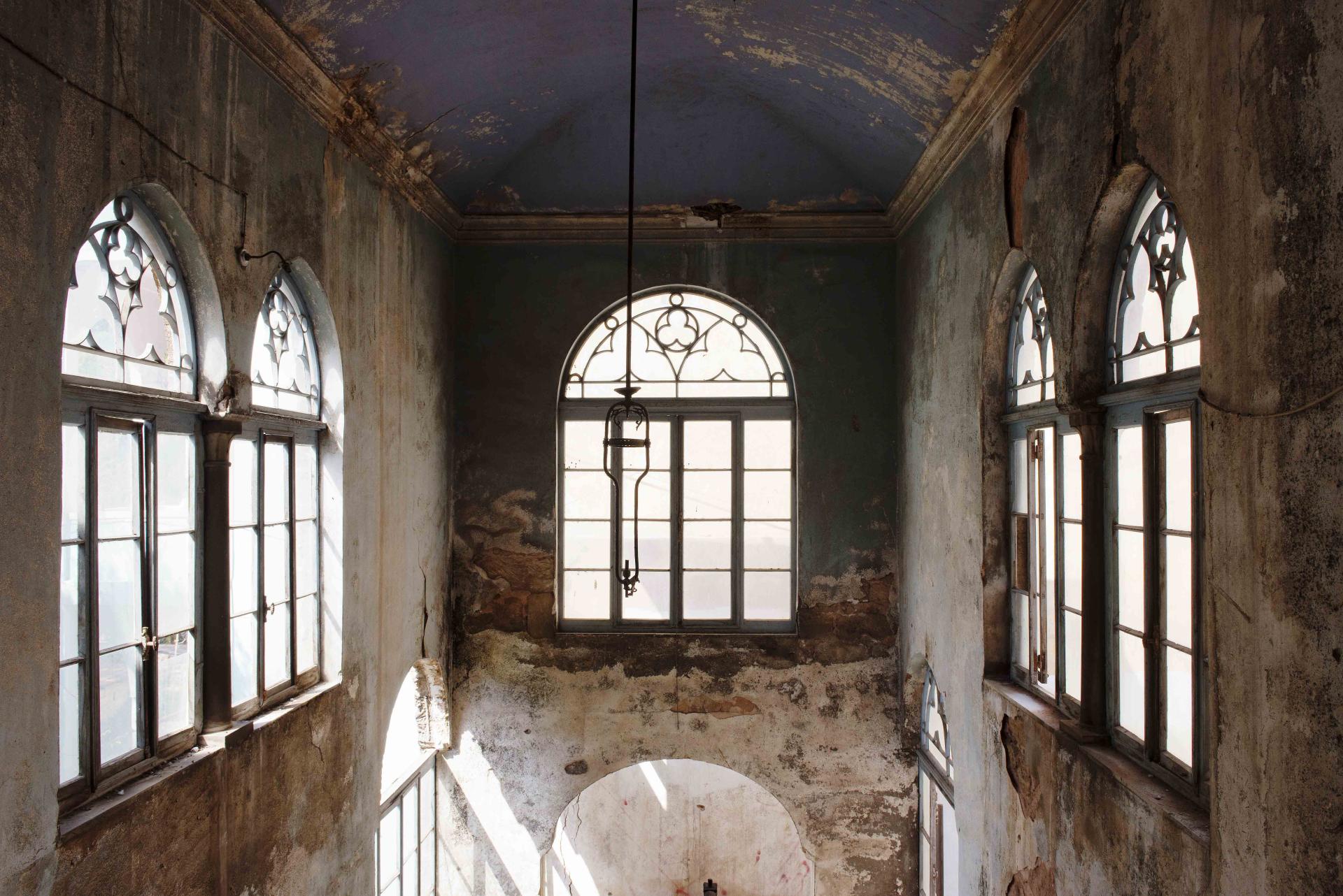 Atrium of a historic 19th-century Lebanese house, featuring arched windows and remnants of original plasterwork.