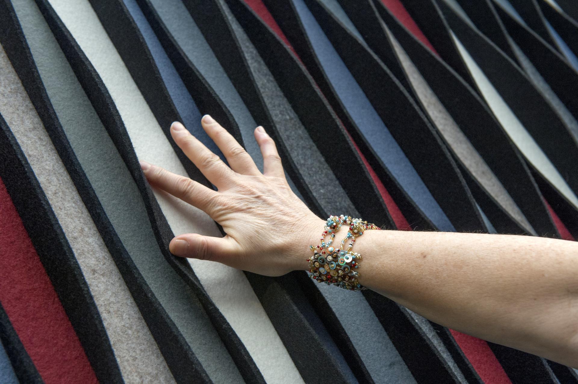 Hand touching textured felt panels in various colors, highlighting innovative surface design at the Surface Design Show.