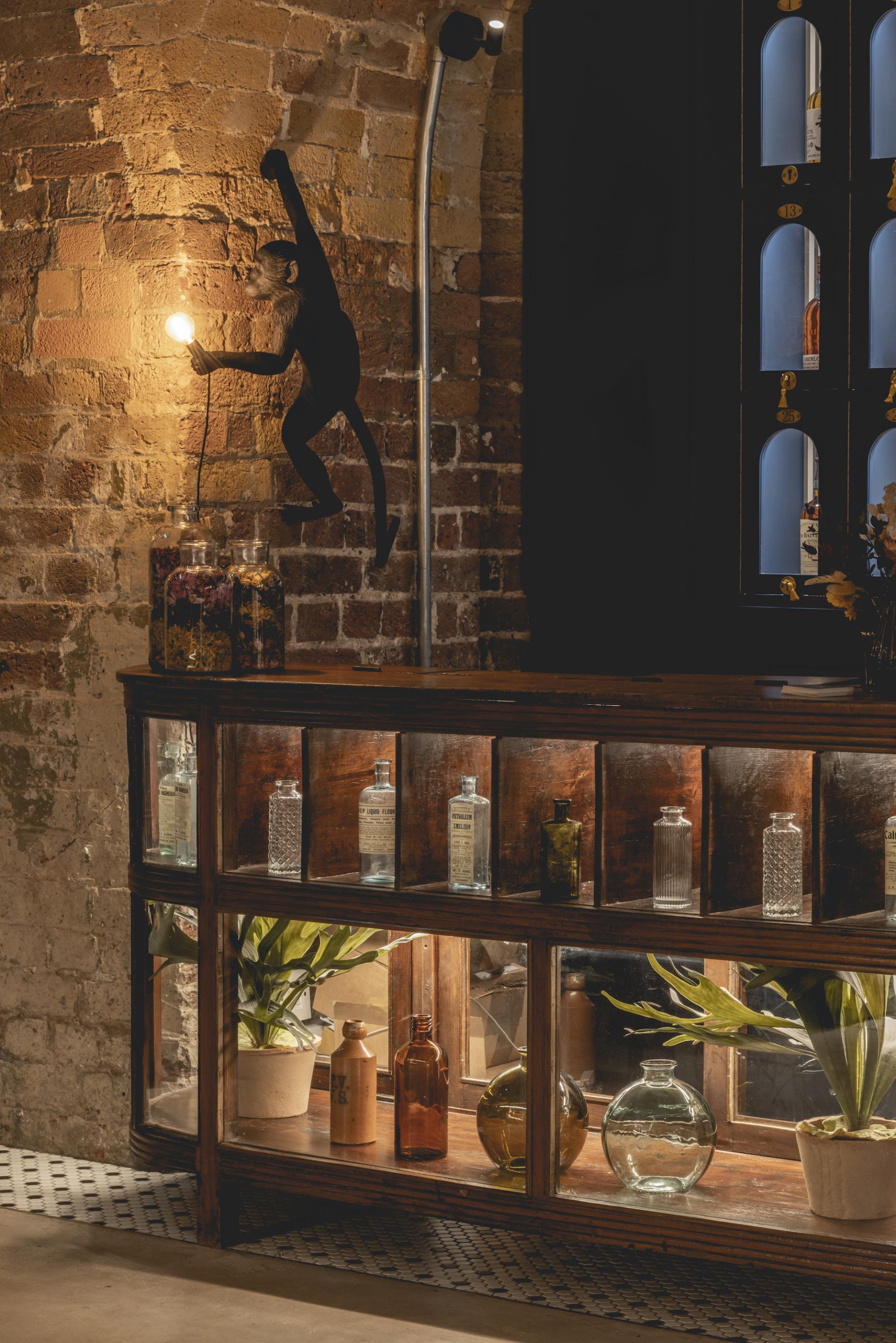Stylish bar area at The Libertine featuring unique lighting and decorative bottles against historic brick walls.