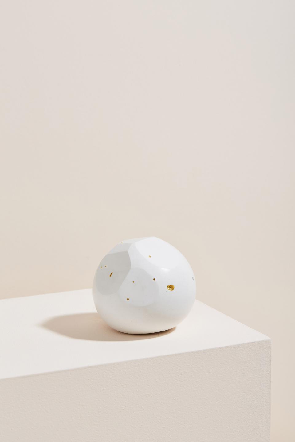 Sculpture by Vic Wright featuring a smooth, white ceramic form with gold accents on a minimalist display.