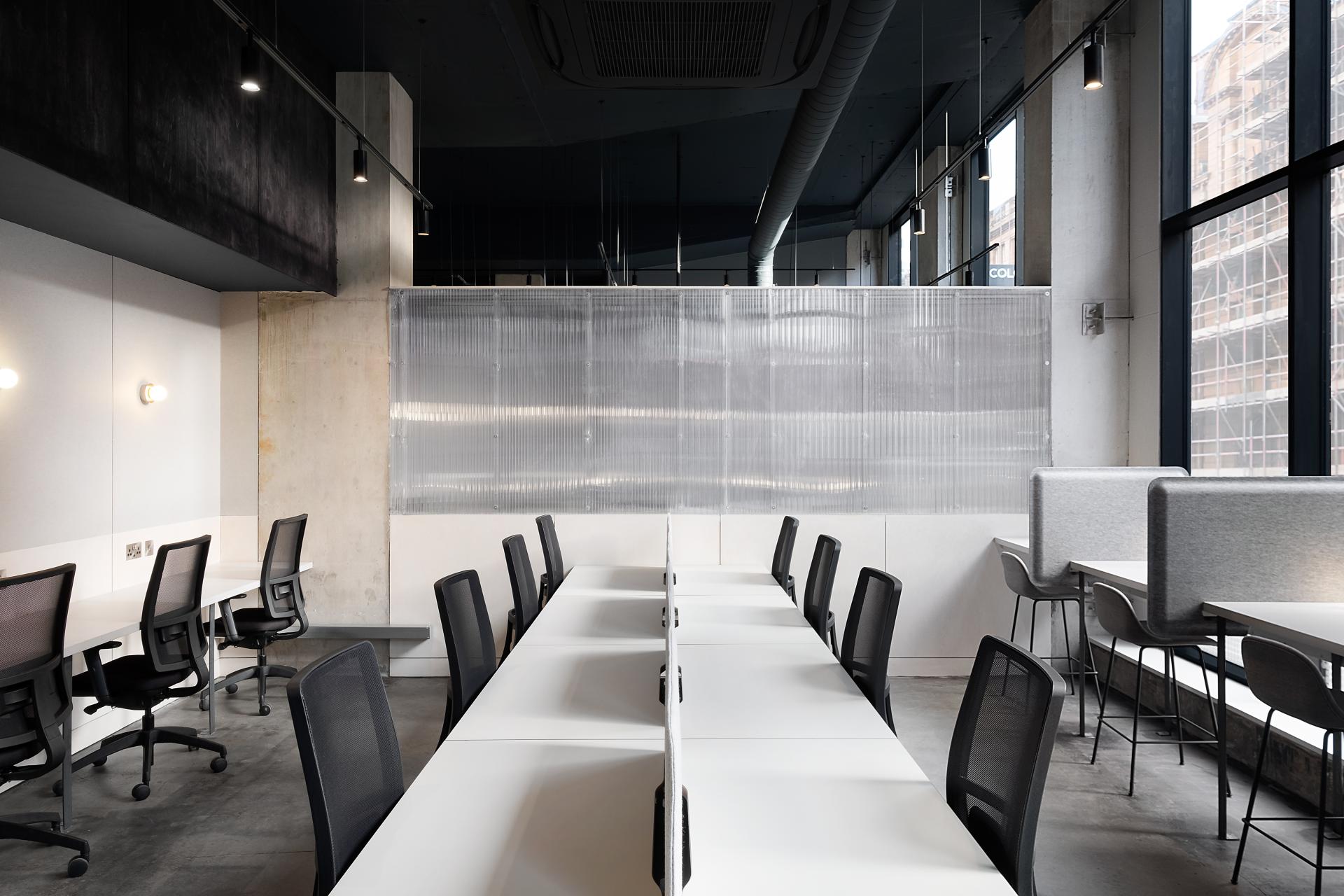 Modern co-working space in Manchester featuring white desks, ergonomic chairs, and contemporary design elements.