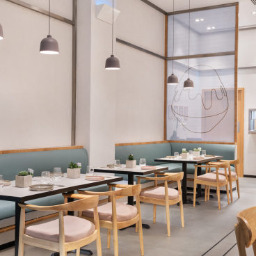 Modern dessert café interior featuring stylish tables, green seating, and minimalist decor for handcrafted desserts.