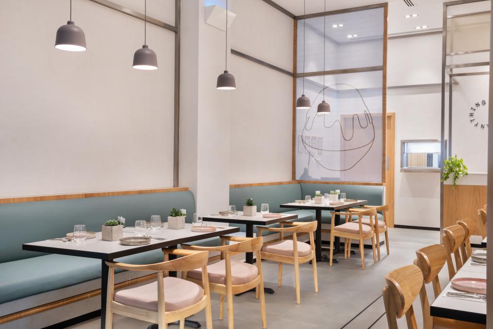 Modern dessert café interior featuring stylish tables, green seating, and minimalist decor for handcrafted desserts.