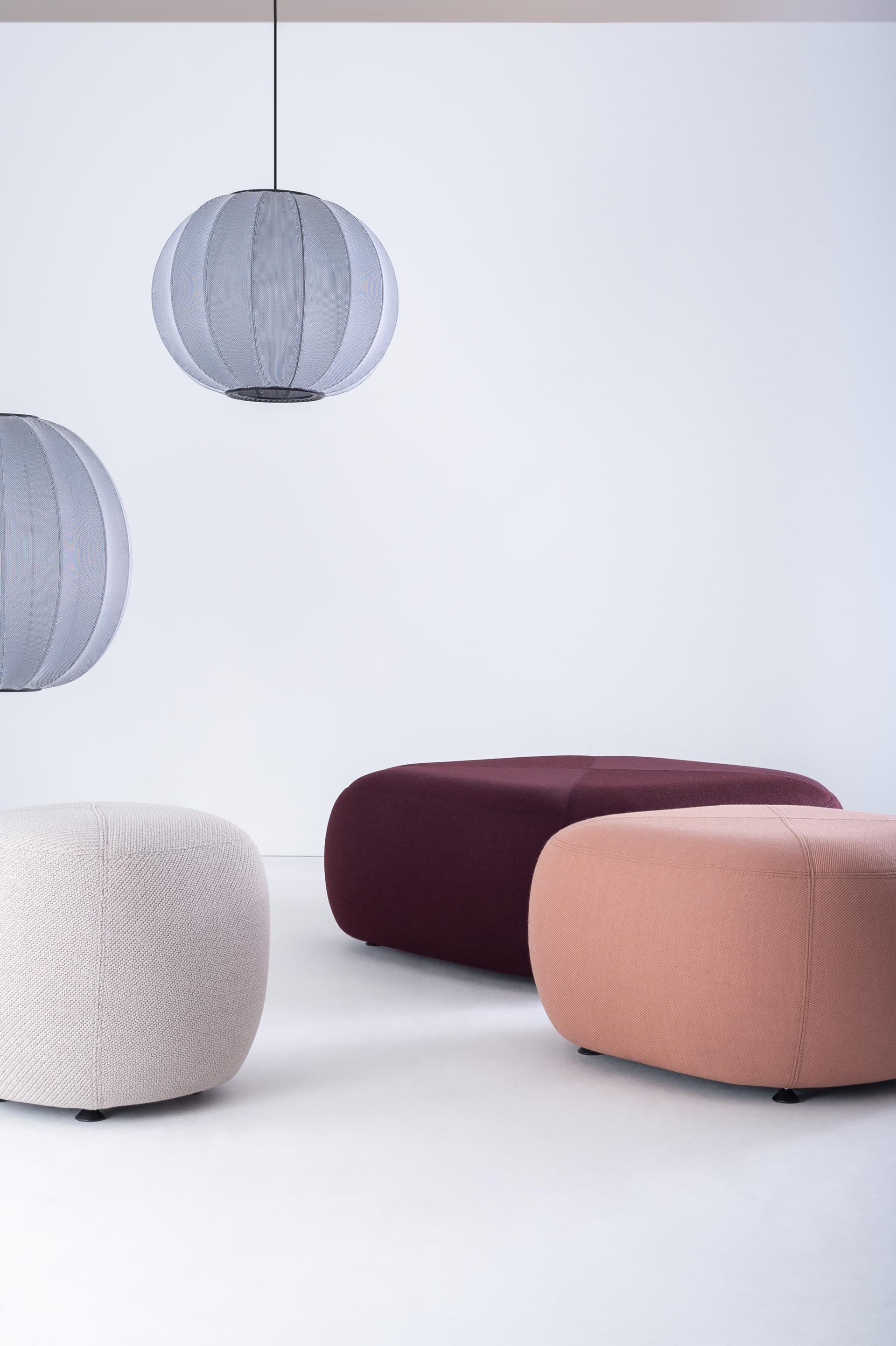 Modern fabric poufs in various colors, complemented by stylish pendant lamps, showcased at designjunction's (Re)act theme exhibit.