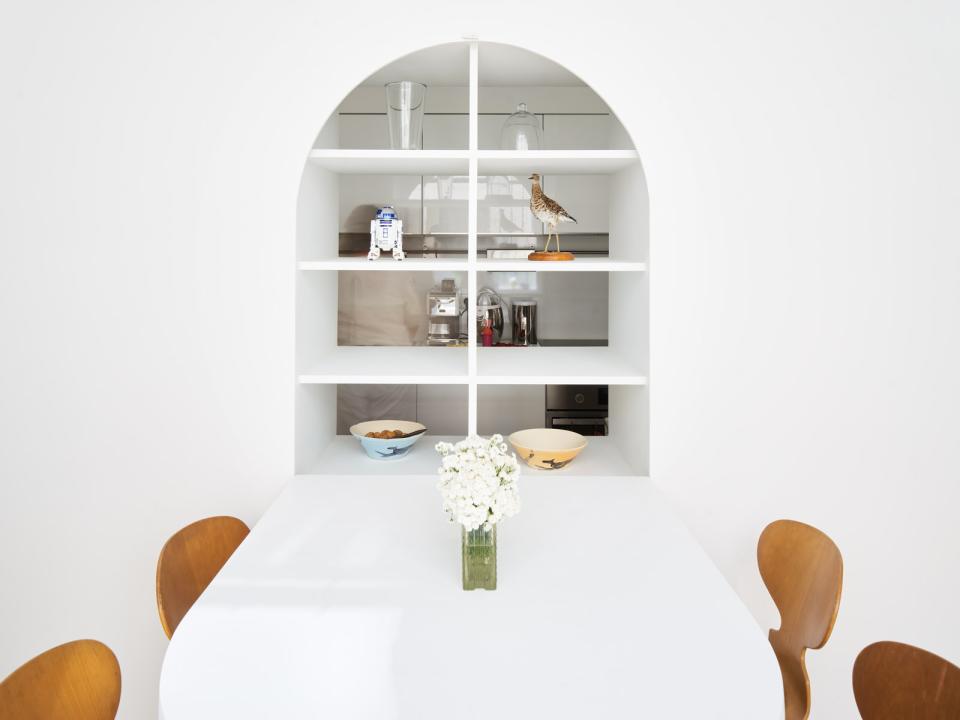 Modern Parisian kitchen featuring a minimalist design, open shelving, decorative items, and a white dining table.