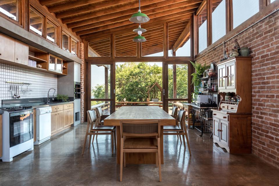 Modern kitchen and dining area in The Lake House, featuring wood accents and large windows overlooking lush greenery.