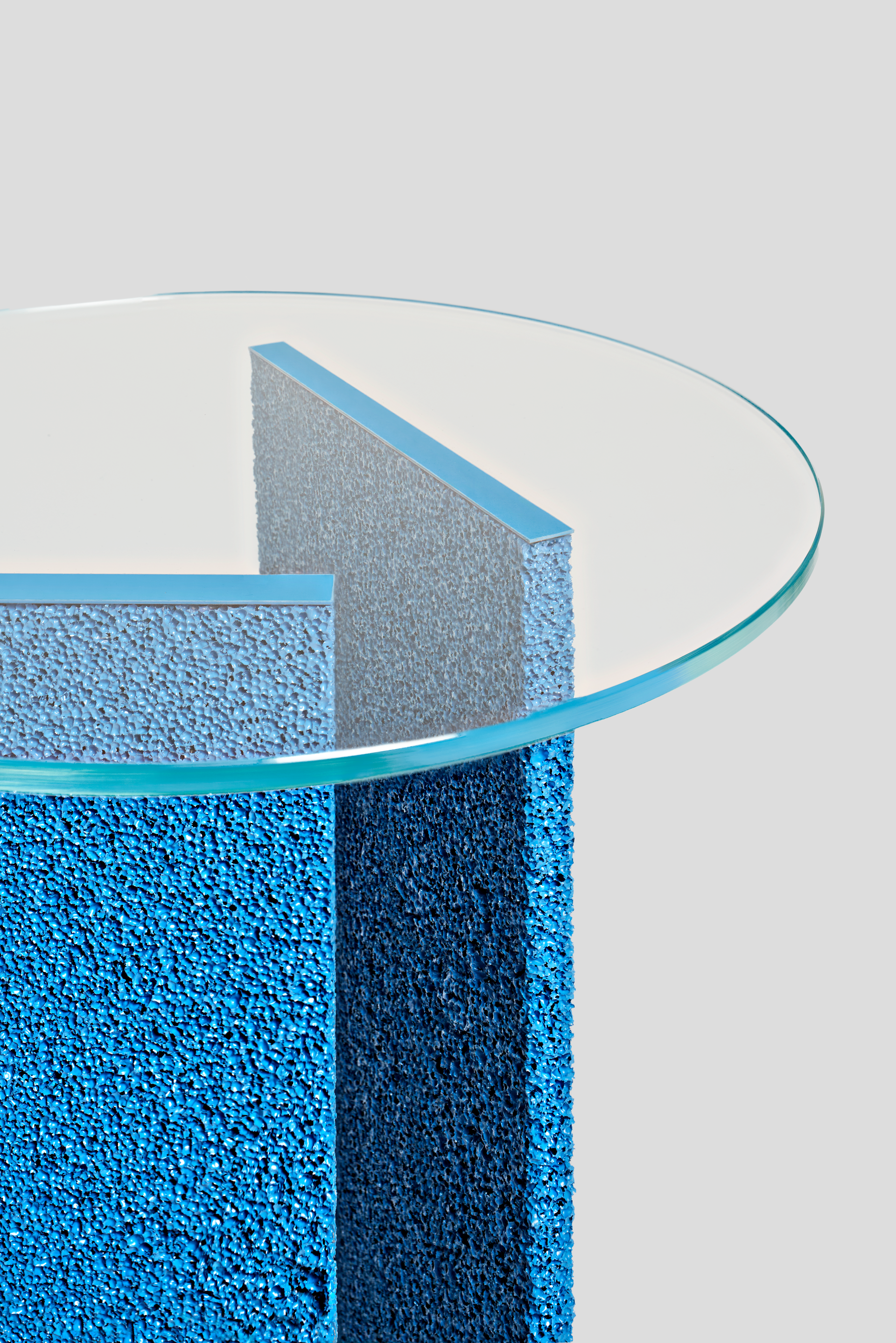 Modern blue sculptural table featuring textured surfaces and a glass top, showcased at London Craft Week 2024.