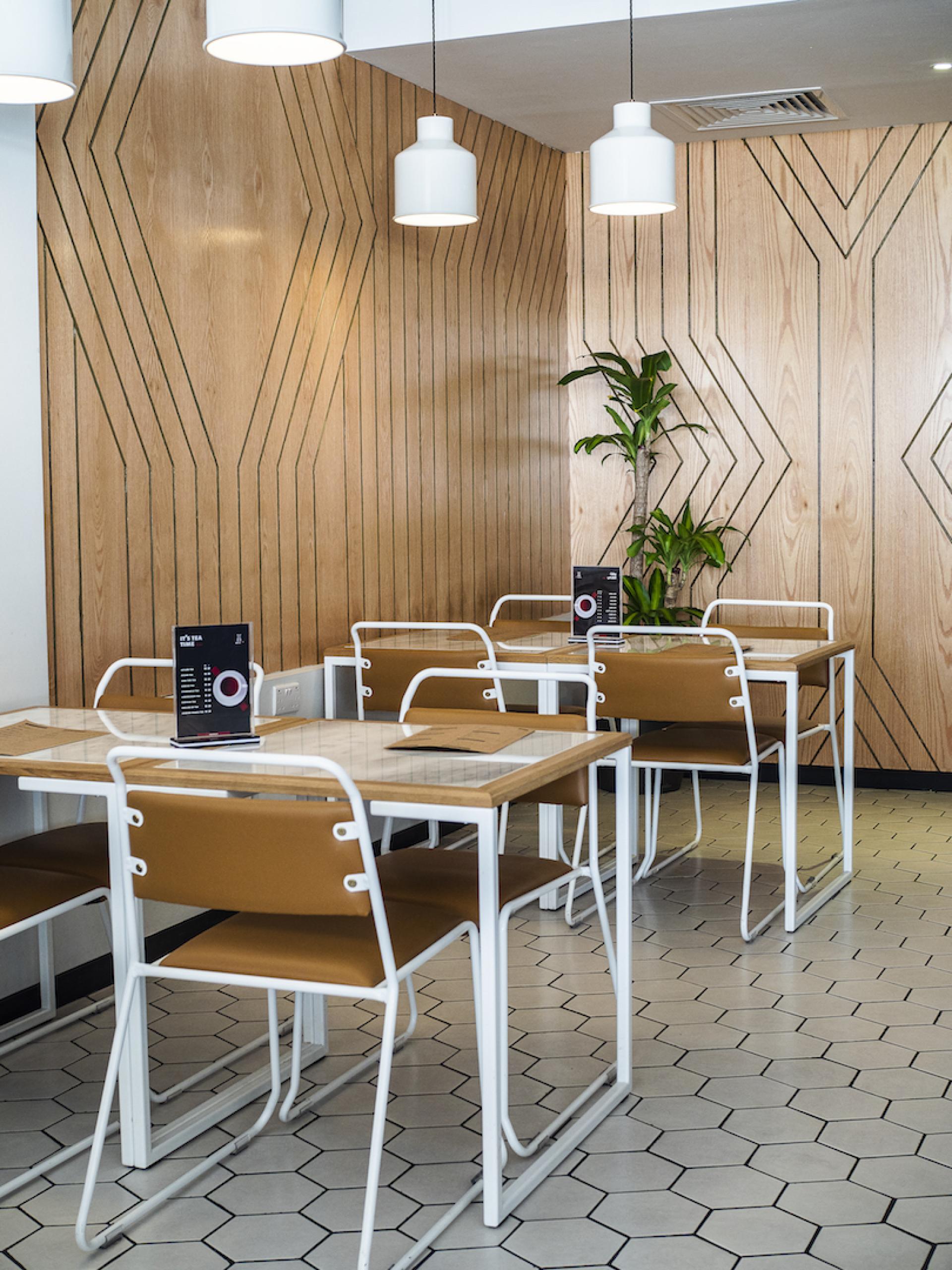 Modern coffee shop interior with wooden paneling, stylish seating, and decorative plant, emphasizing specialty coffee design.