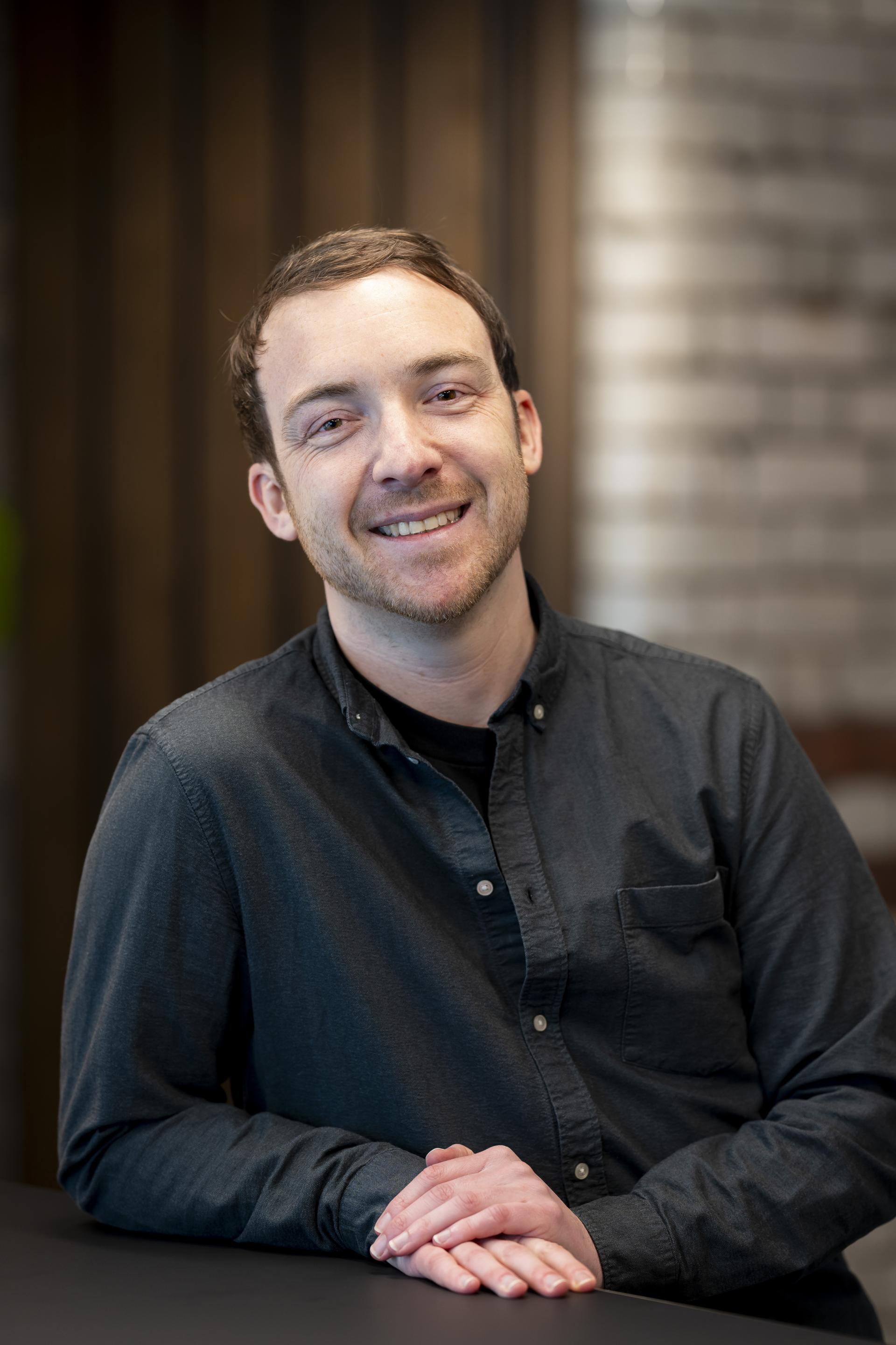 Smiling man in a dark shirt discusses technology's role in sustainable design, promoting innovation in the industry.