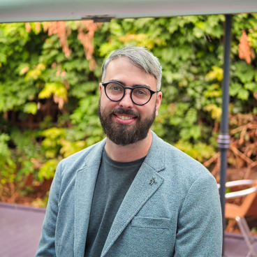Matt Redding, associate at Gensler, smiling in front of greenery, reflecting on ESG principles for sustainable architecture.