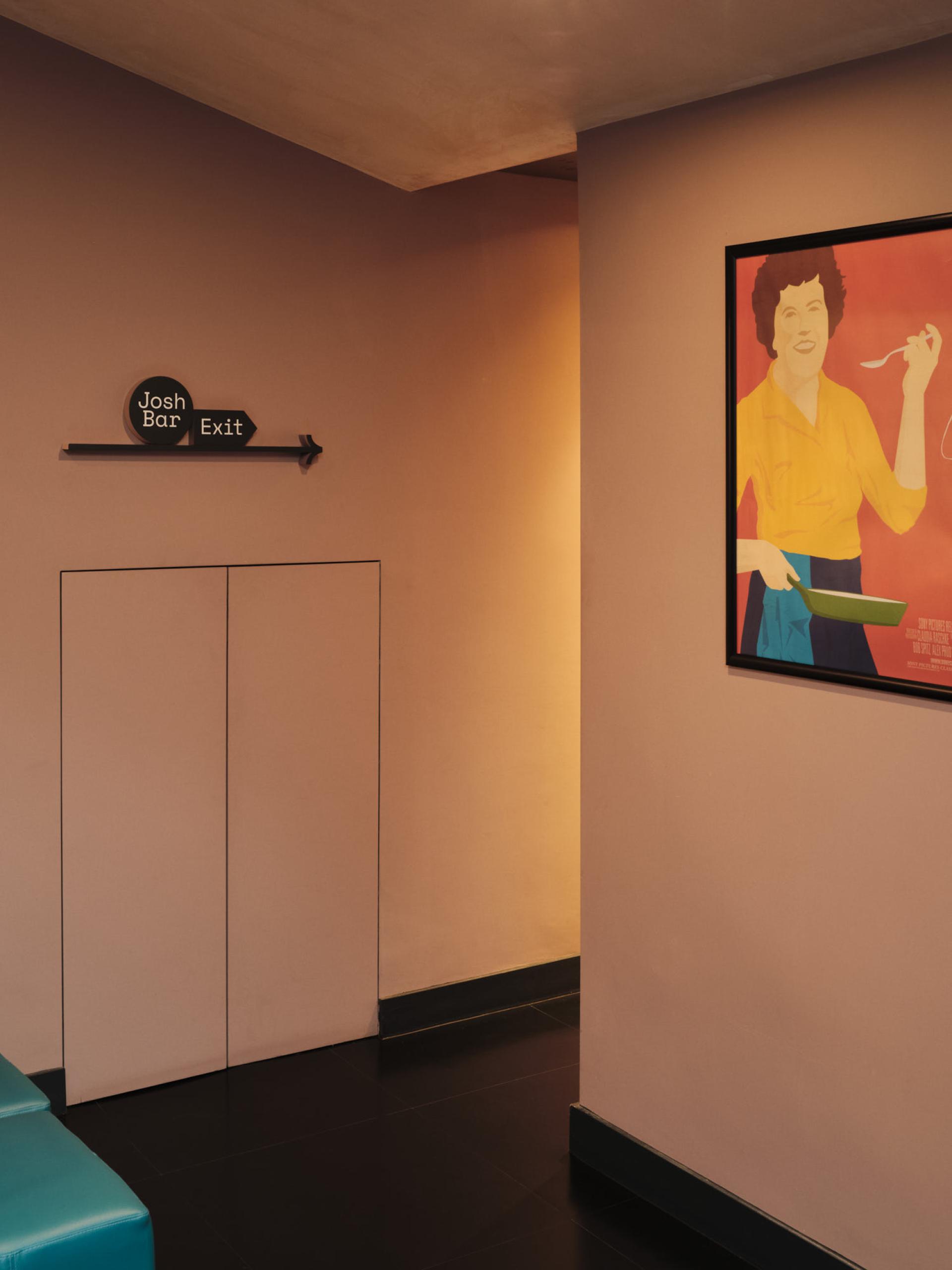 Interior view of The Lexi cinema, showcasing a wall sign for the bar and a vibrant framed artwork.