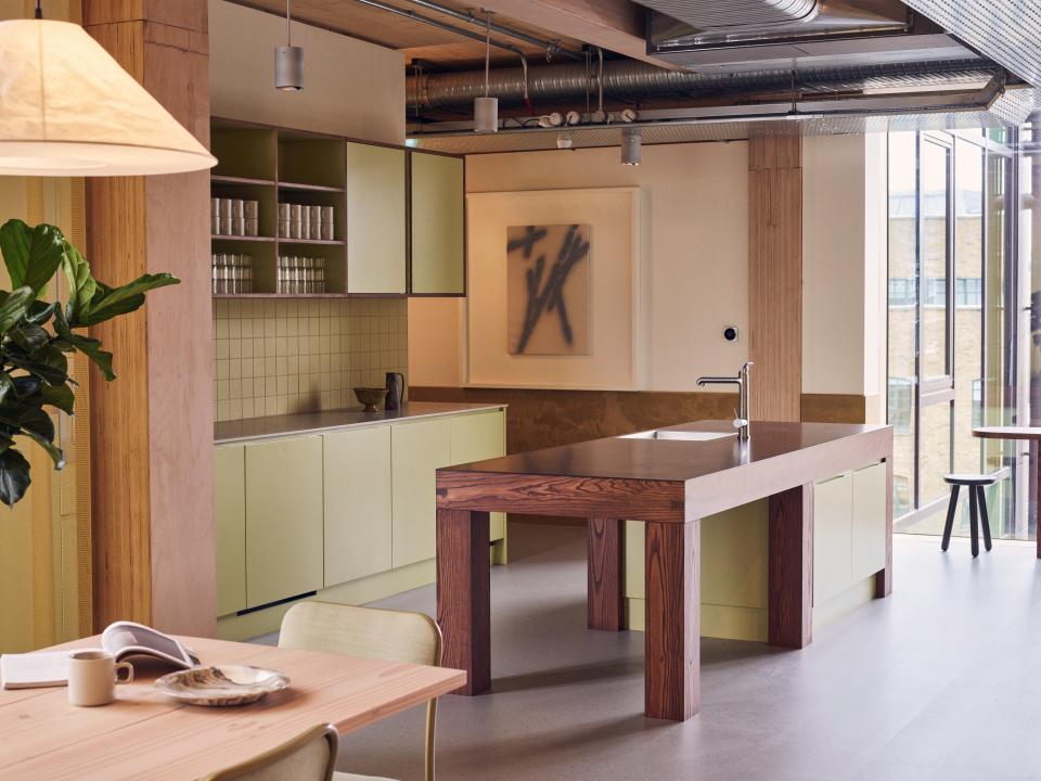 Modern sustainable kitchen design featuring a wooden island and green cabinetry in the Black & White Building.