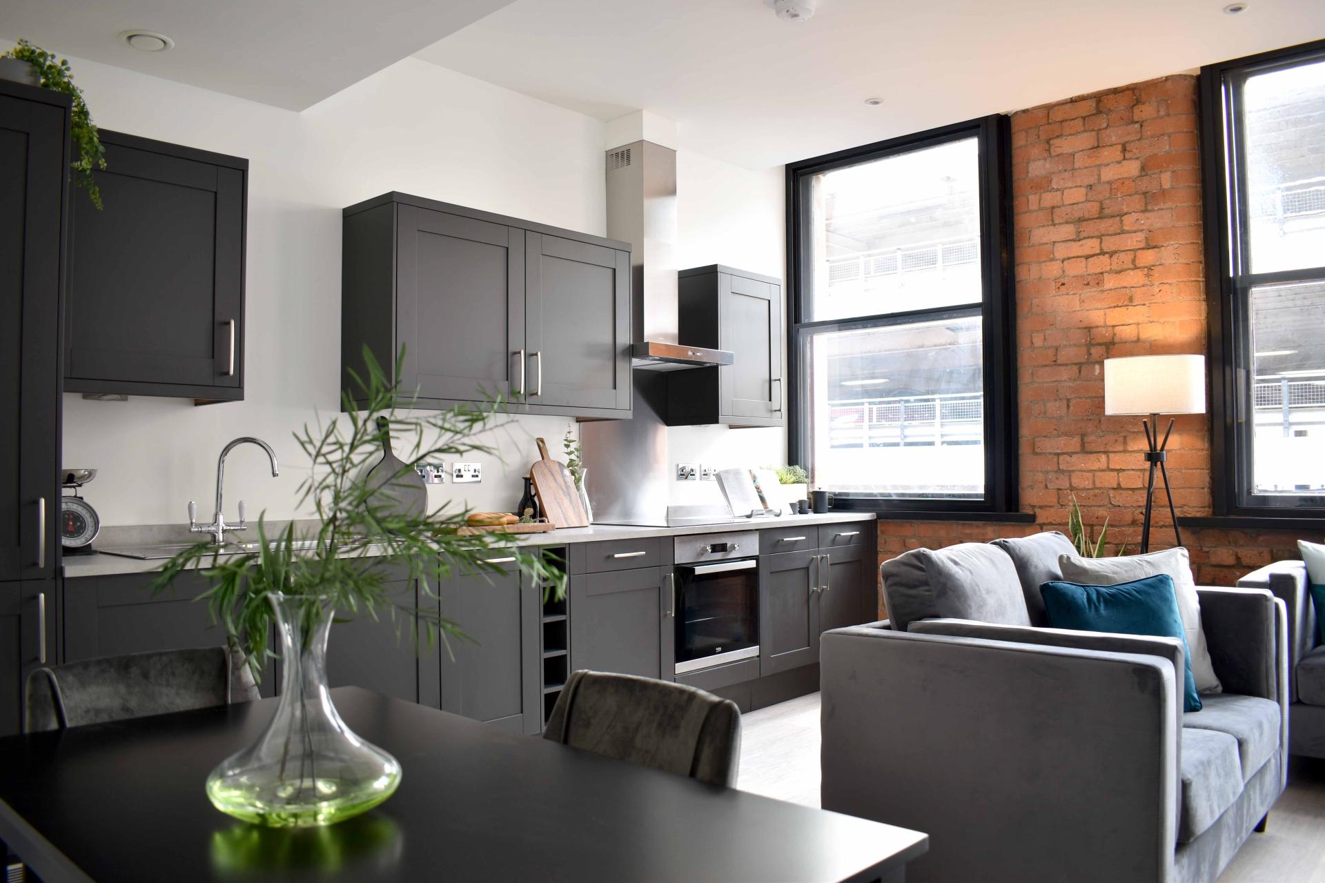 Modern kitchen and living area featuring sleek cabinetry, large windows, and a cozy atmosphere, showcasing Kamani Property Group's design.