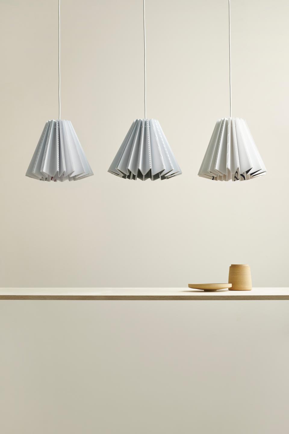 Sustainable sculptural lampshades designed by Tabitha Bargh, made from everyday materials, hanging above a minimalist wooden shelf.